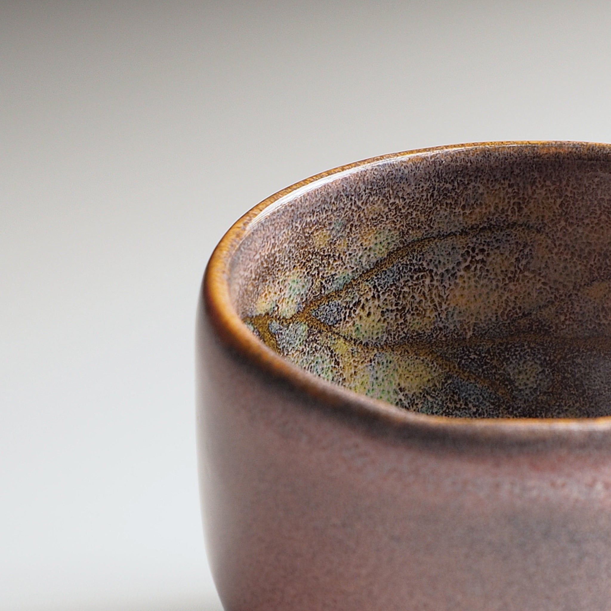 Close-up of a pink ceramic yunomi teacup with textured surface on a light gray background