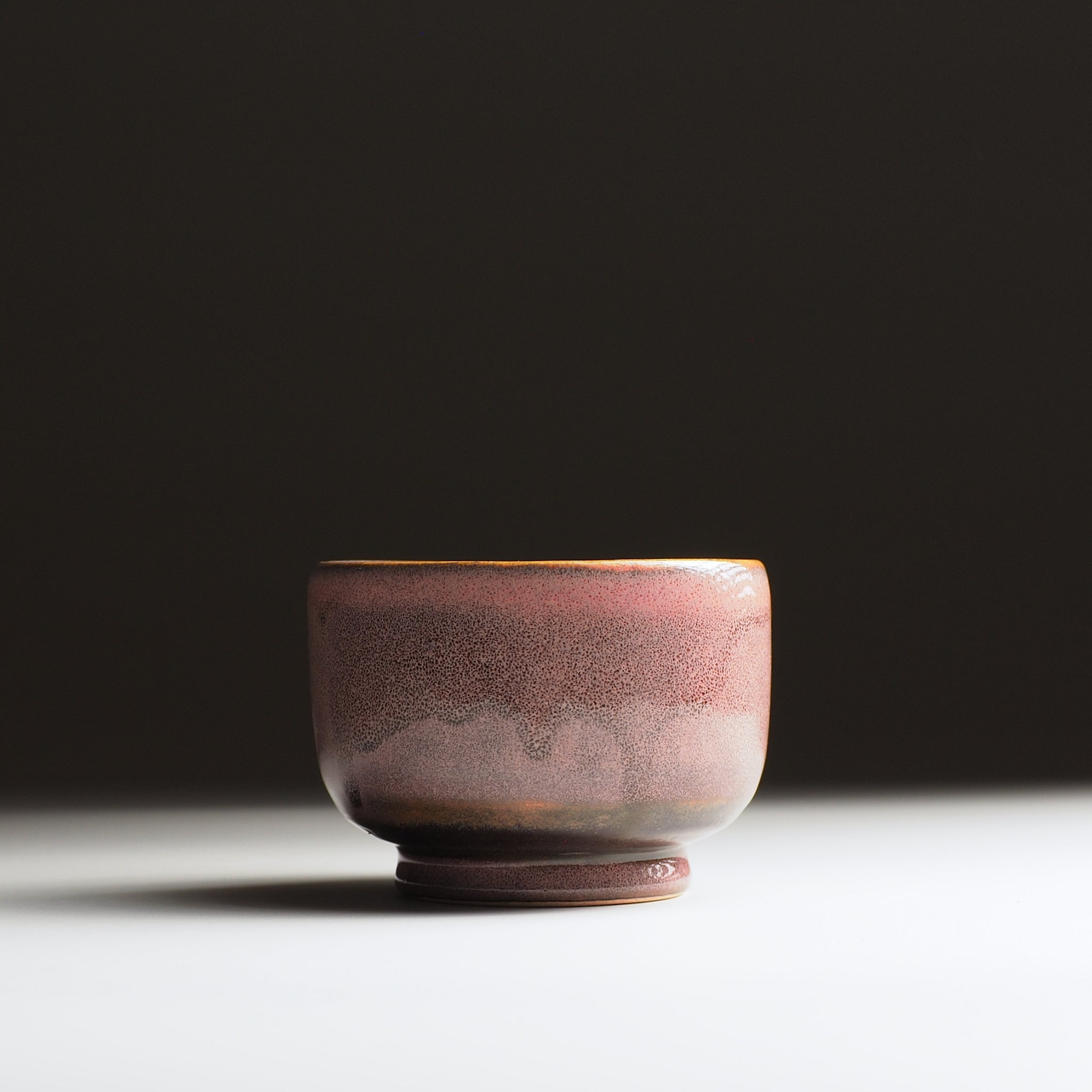 Front view of a Japanese pink yunomi on a faded background.