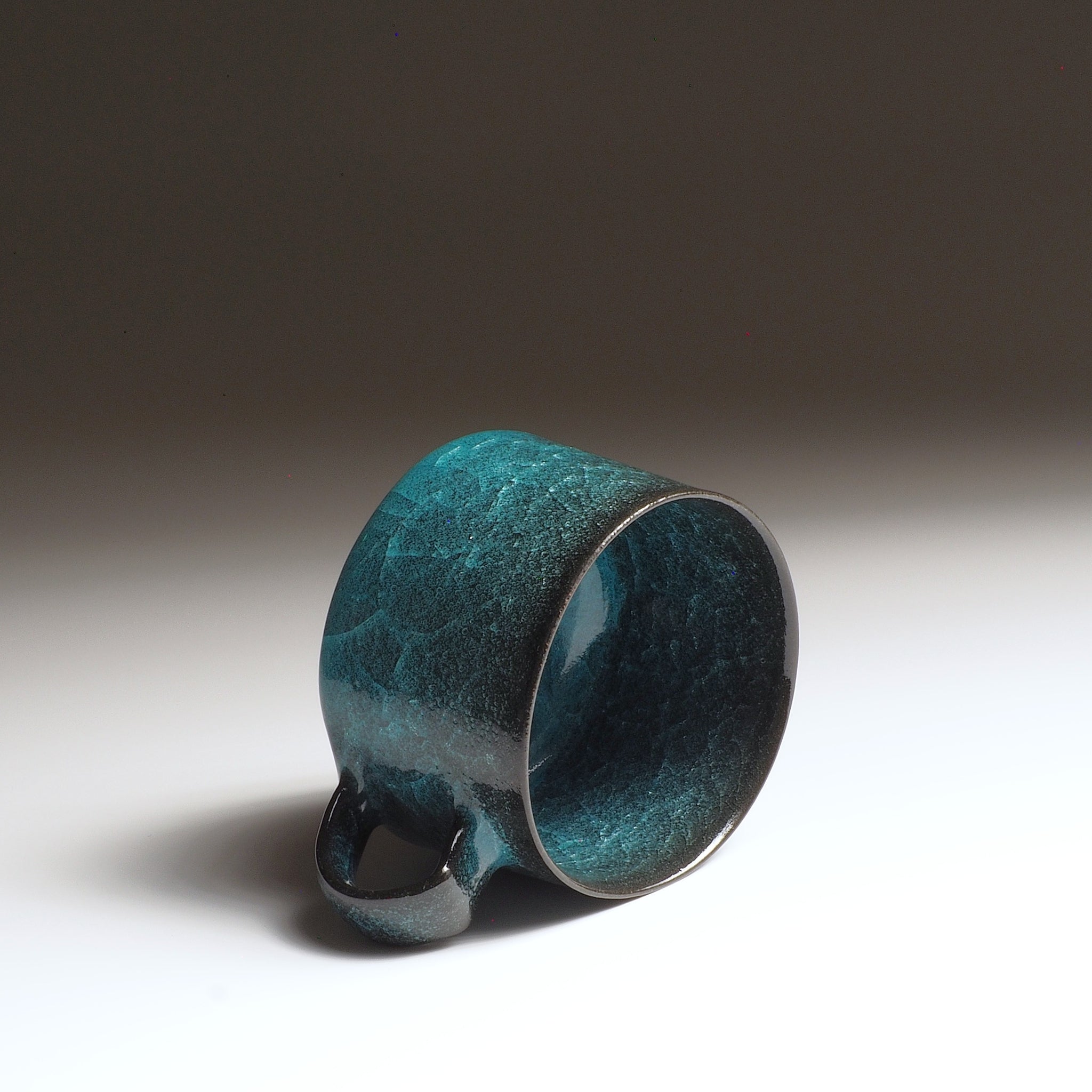 Interior view of handcrafted Japanese pottery coffee cup  Seika, with kannyū ceramic crazing glaze in emerald green.