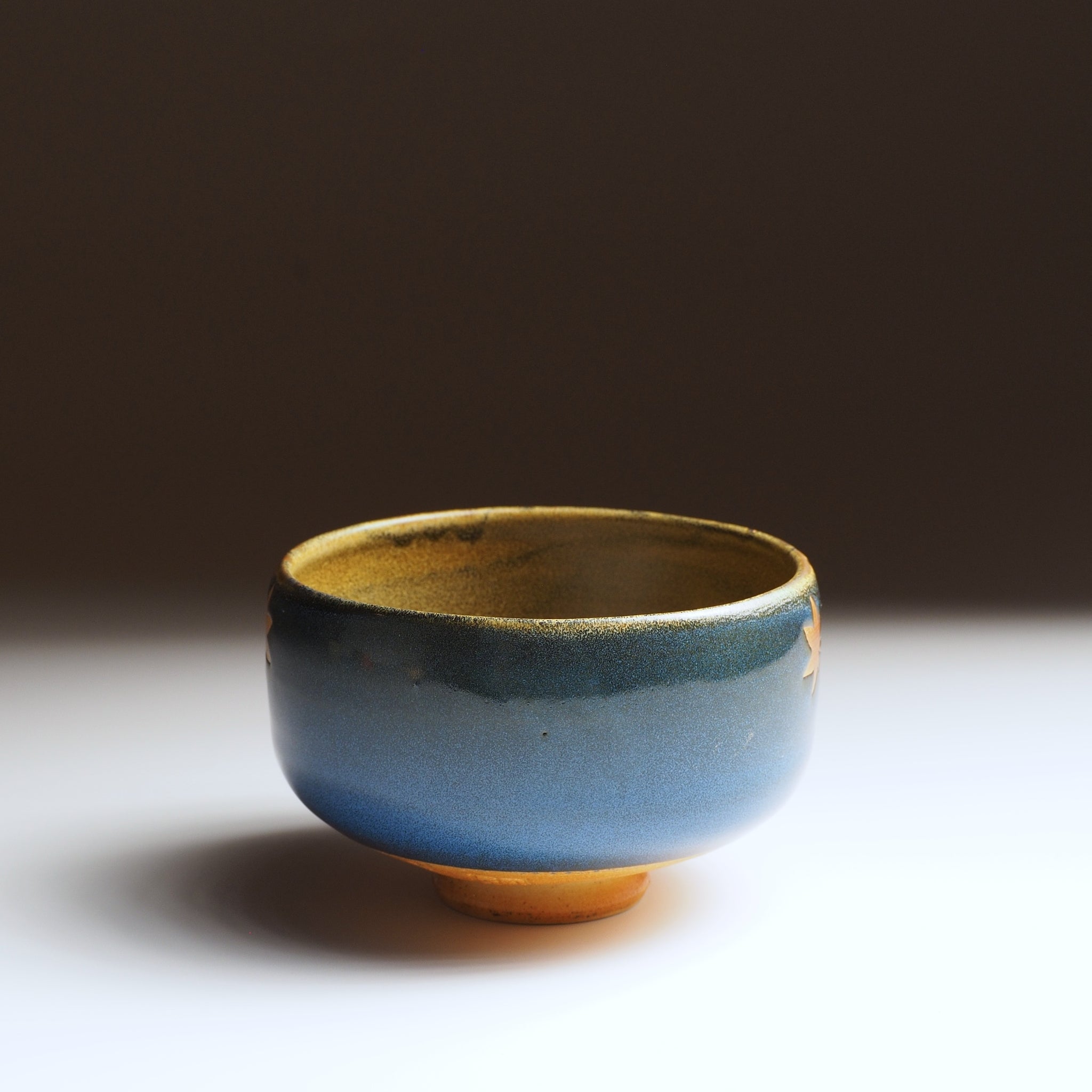Sōshū matcha bowl, front view, plain blue Nanasai Tenmoku glaze side, unglazed amber rim and foot ring
